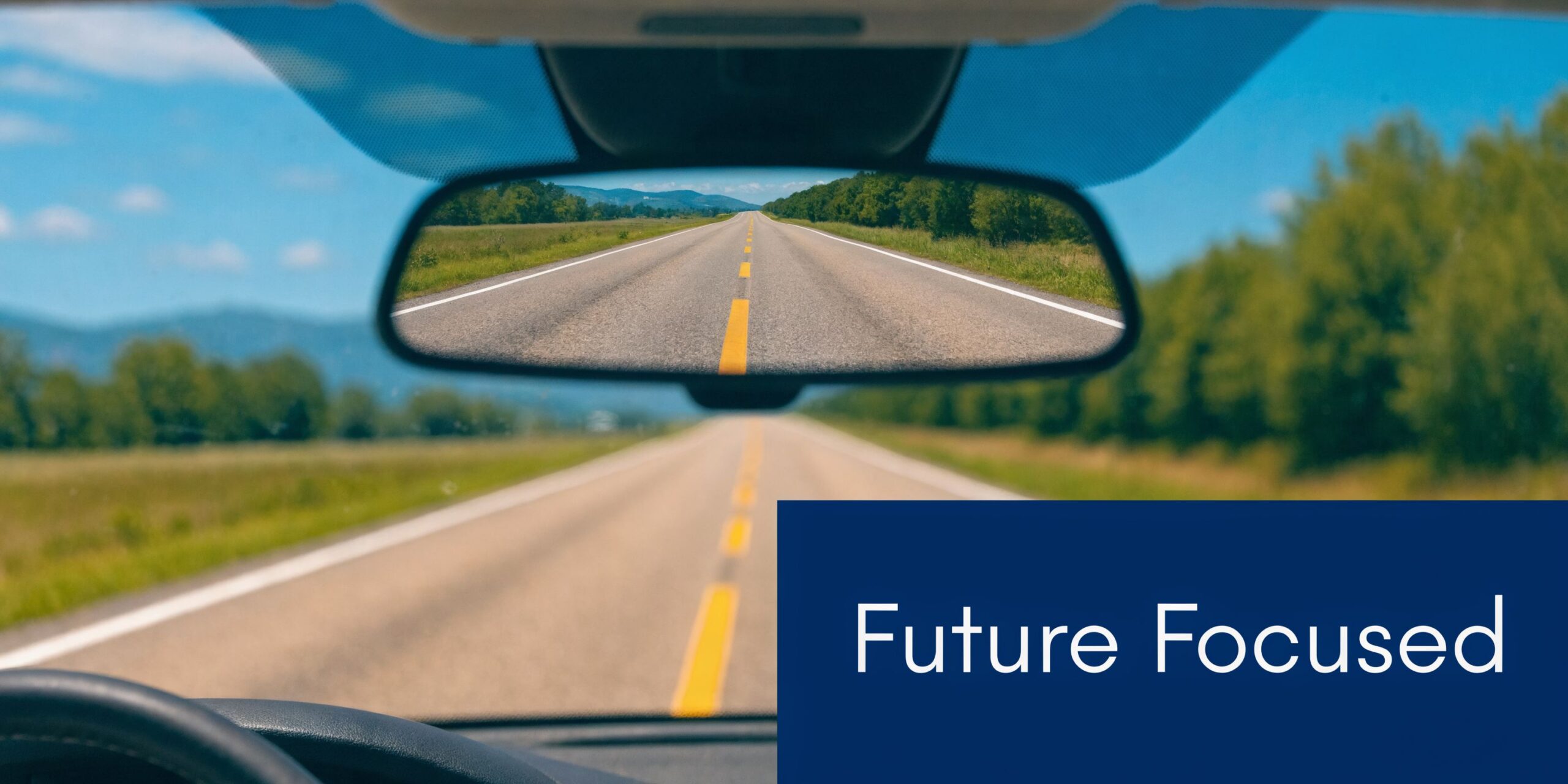 A view through a car windshield showing a road ahead with a future focused sign.