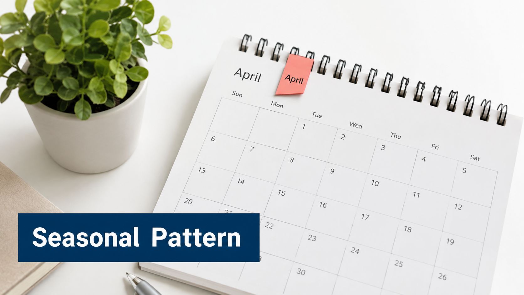 A calendar showing the month of April placed on a white desk next to a potted plant.